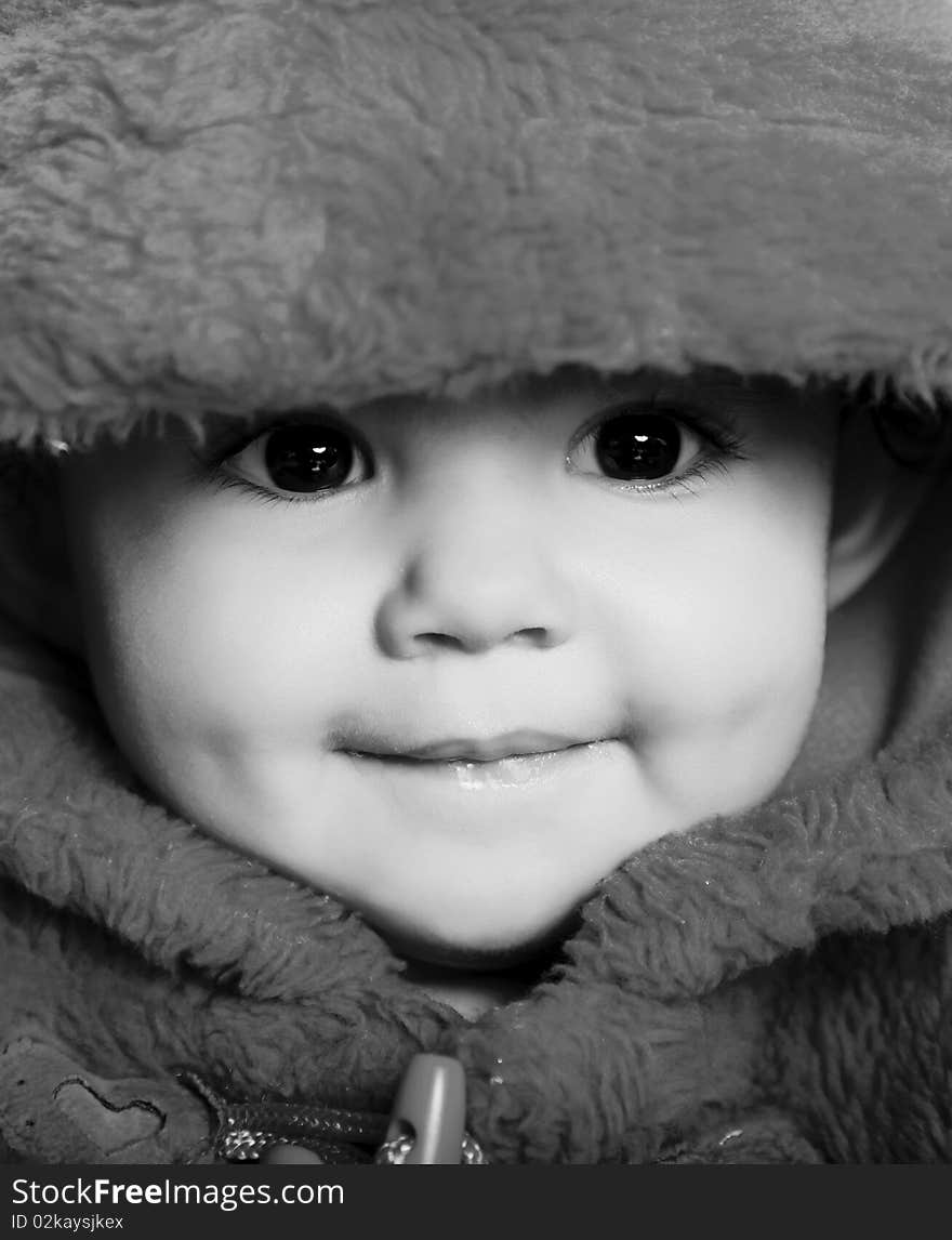 Girl looking at the camera and smiling with hood. Black and white image. Girl looking at the camera and smiling with hood. Black and white image