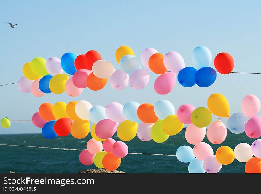 Lots of colorful balloons on background with blue sky and sea