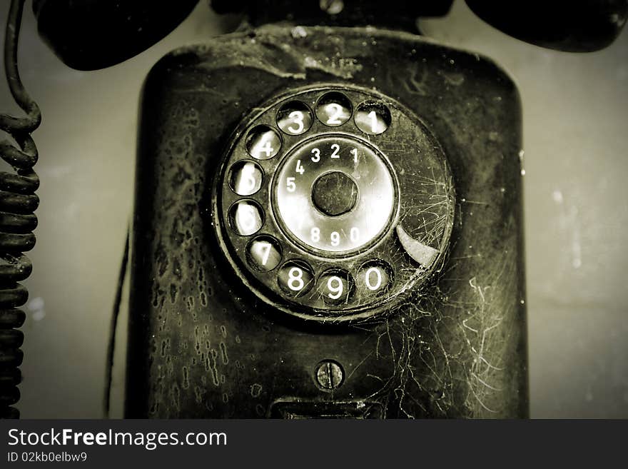 Old and black phone over black background