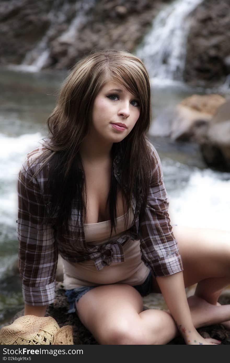 A beautiful woman dressed like a cowgirl on a rock by the river. A beautiful woman dressed like a cowgirl on a rock by the river.