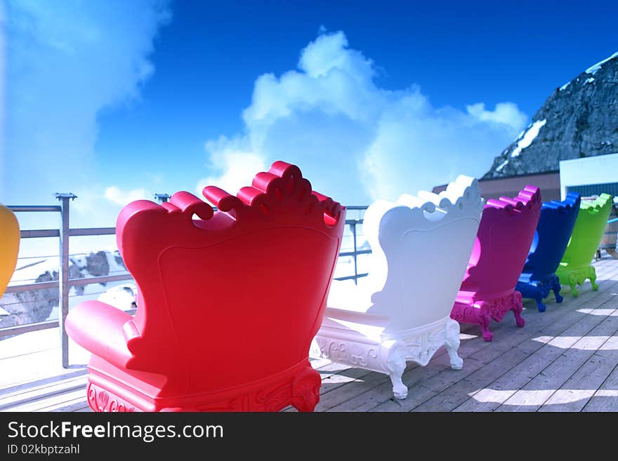 Colourful armchairs stand on a background mountains and blue sky