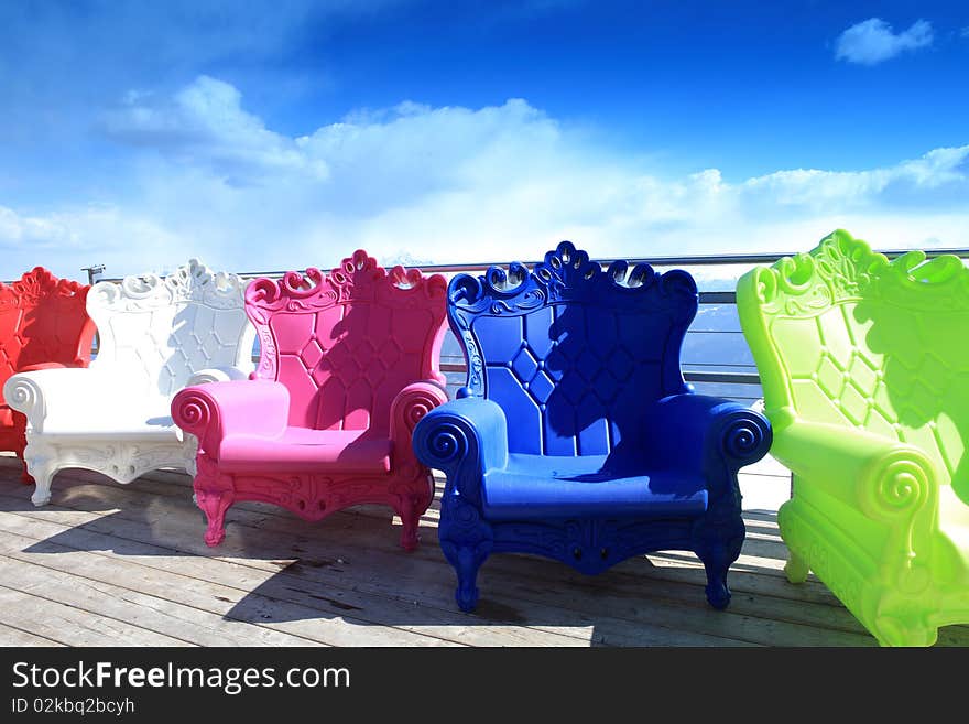 Multi-colored armchairs stand outdoor against the background the blue sky