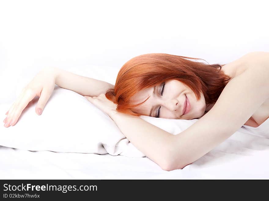 Red-haired girl in bed. Studio shot.