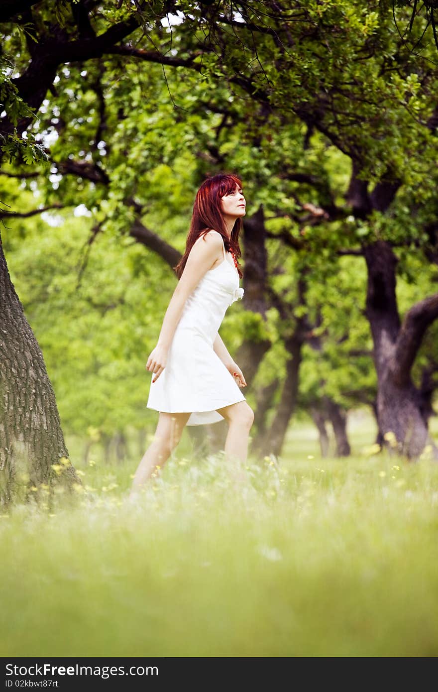 Beautiful woman in white walking through the green forest in summer. Beautiful woman in white walking through the green forest in summer