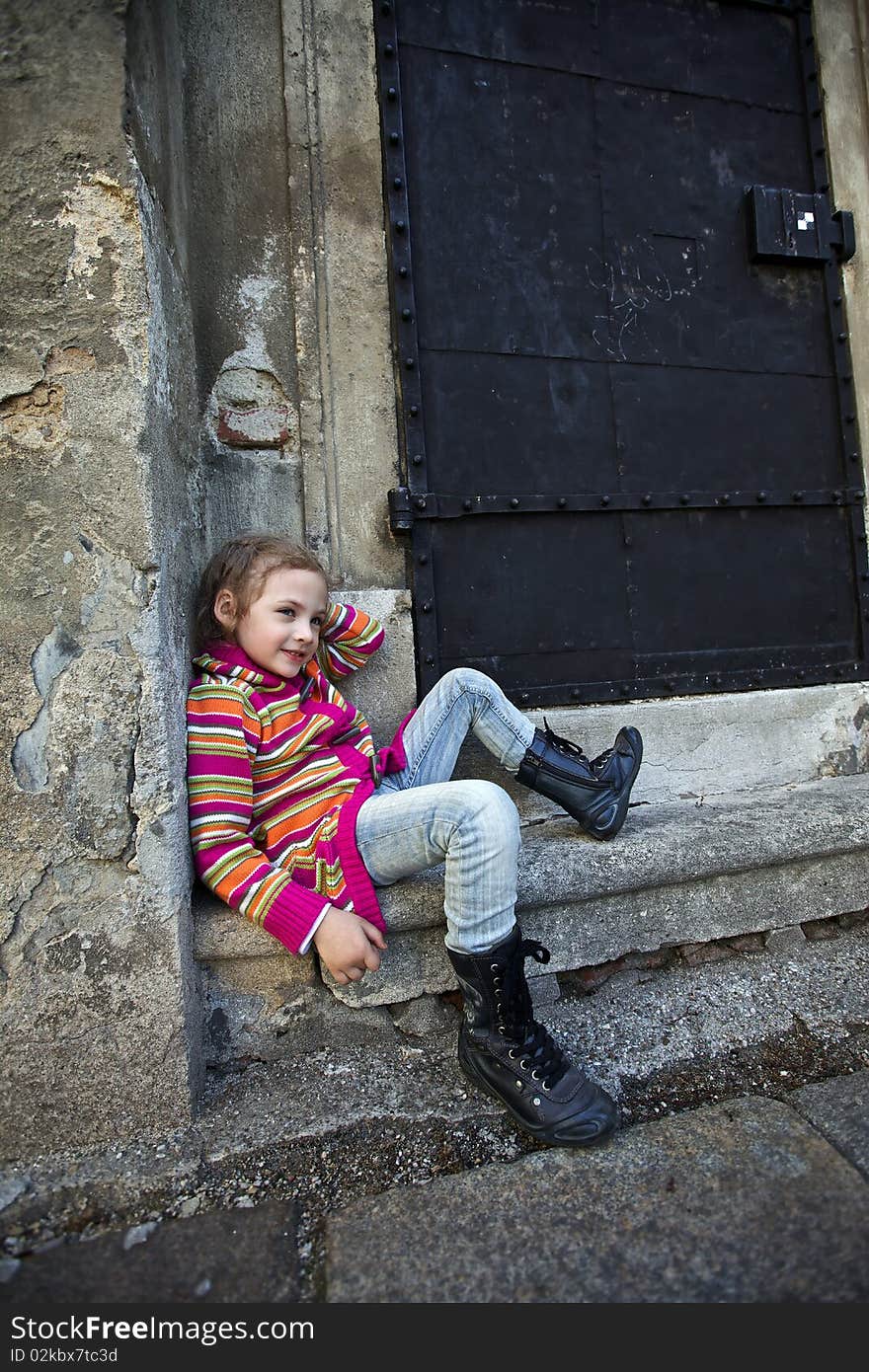 A girl sitting on steps on old wall background