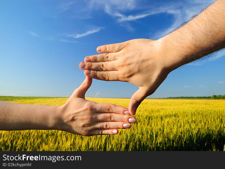 Hands form a rectangle against a wheaten field. Hands form a rectangle against a wheaten field