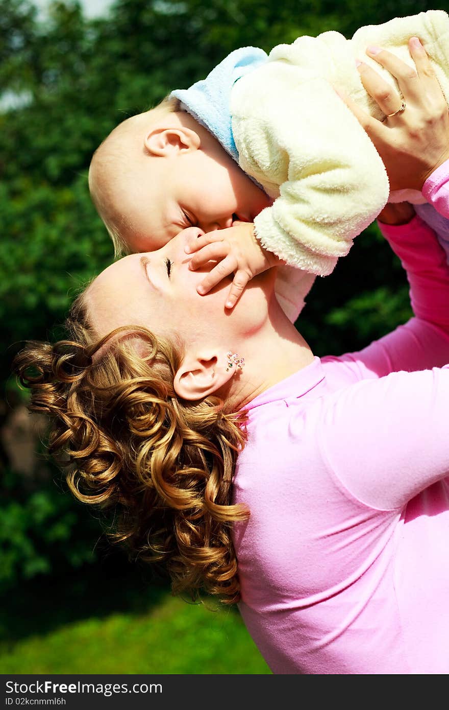 Young beautiful mother and her baby outdoor in the park in summertime. Young beautiful mother and her baby outdoor in the park in summertime