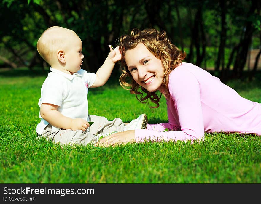 Young beautiful mother and her baby outdoor in the park in summertime. Young beautiful mother and her baby outdoor in the park in summertime