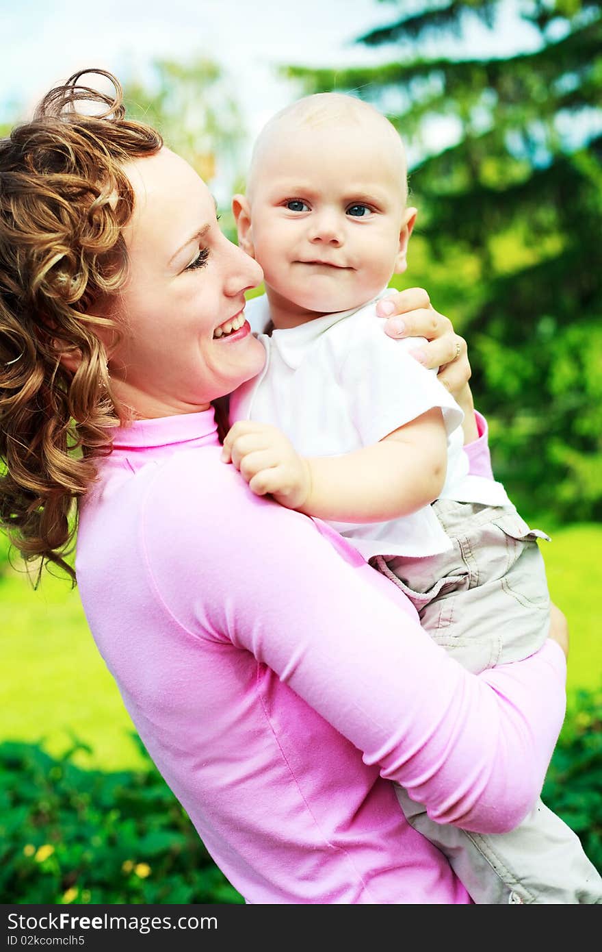 Young beautiful mother and her baby outdoor in the park in summertime. Young beautiful mother and her baby outdoor in the park in summertime