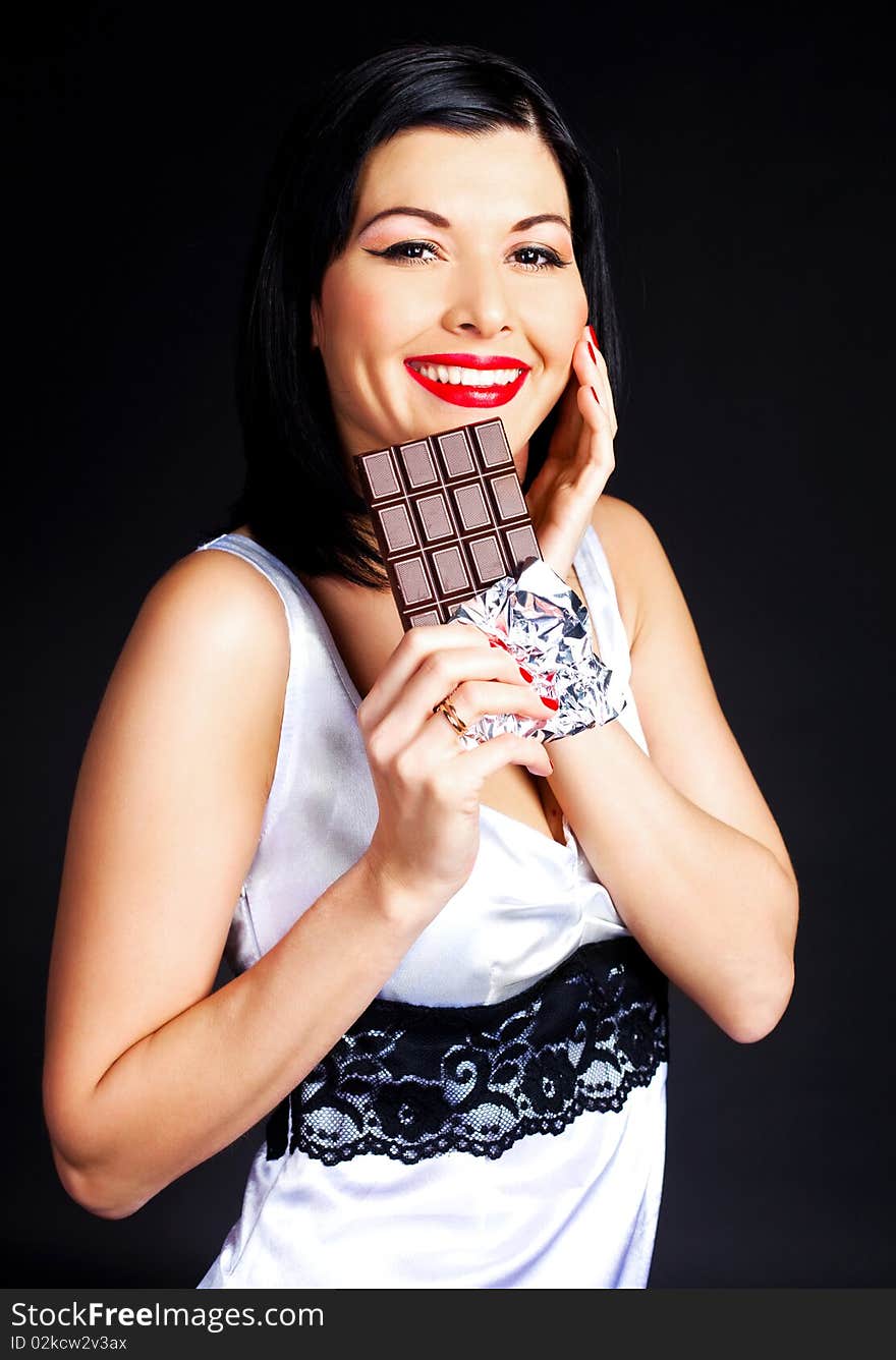 Pretty happy young brunette woman eating dark chocolate. Pretty happy young brunette woman eating dark chocolate