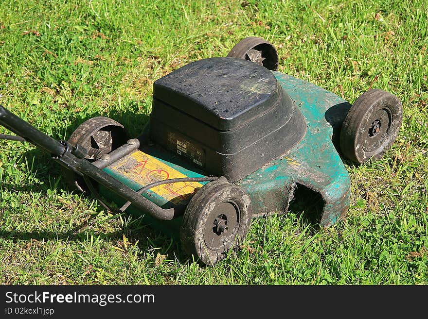 Dirty green lawnmower in garden