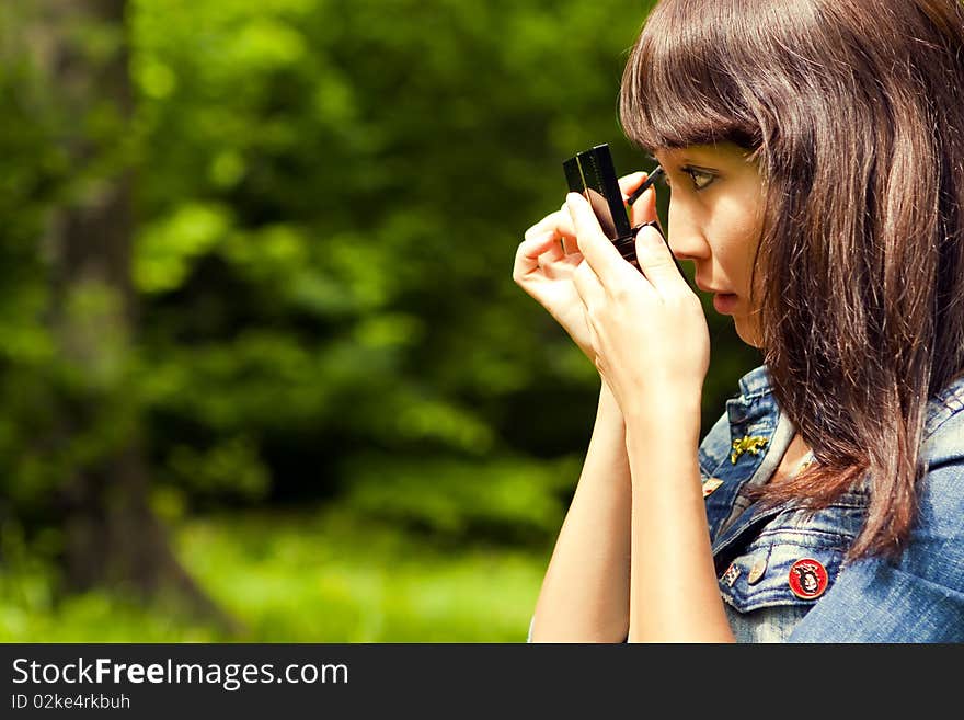 Oriental woman apply makeup on the nature. Oriental woman apply makeup on the nature