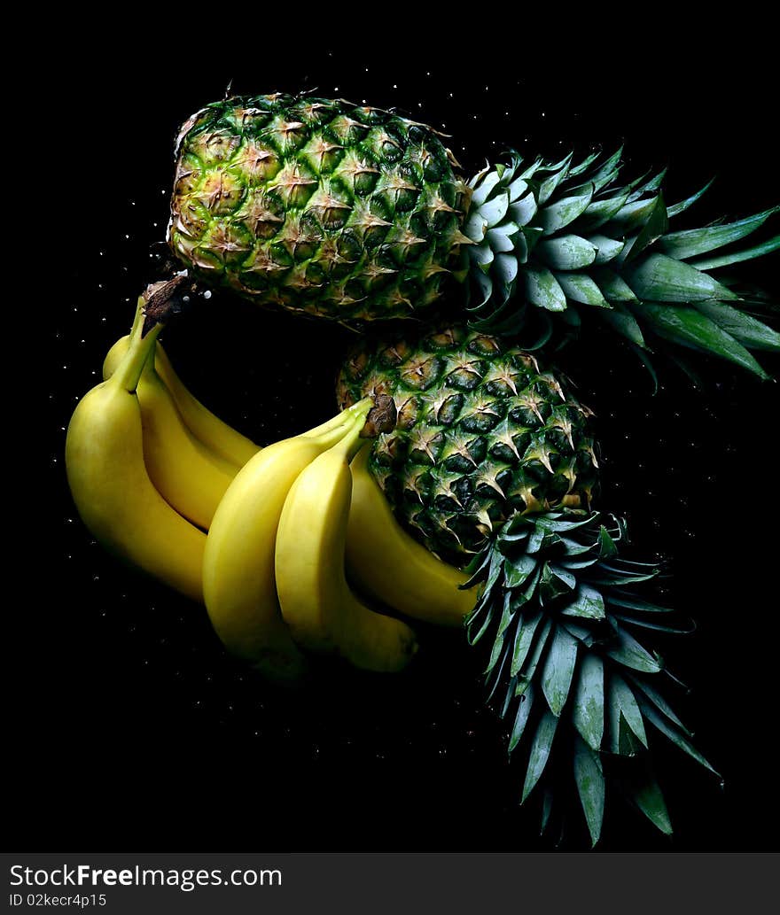 Bananas and pineapple on black background