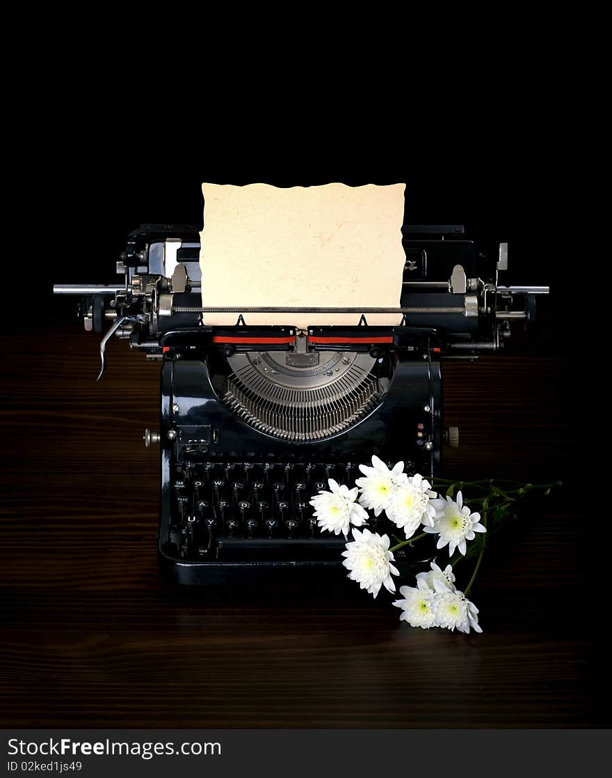 Antique typing machine with paper for text and flowers on dark background. Antique typing machine with paper for text and flowers on dark background