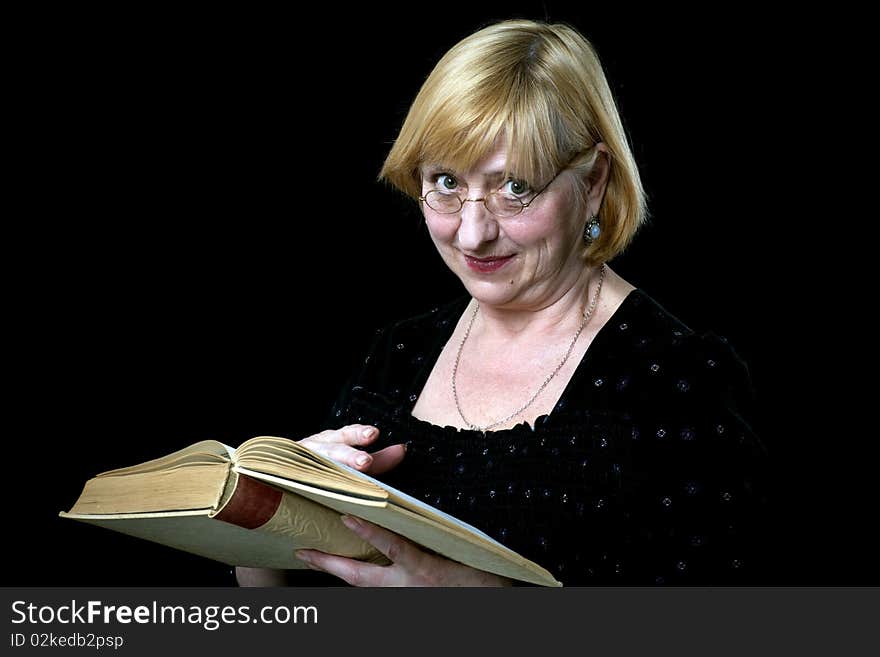 Happy senior woman with book and glasses on black background