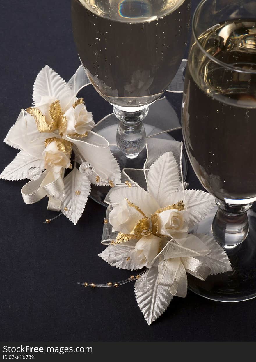 Glasses with champagne and weddings buttonholes  on a dark background