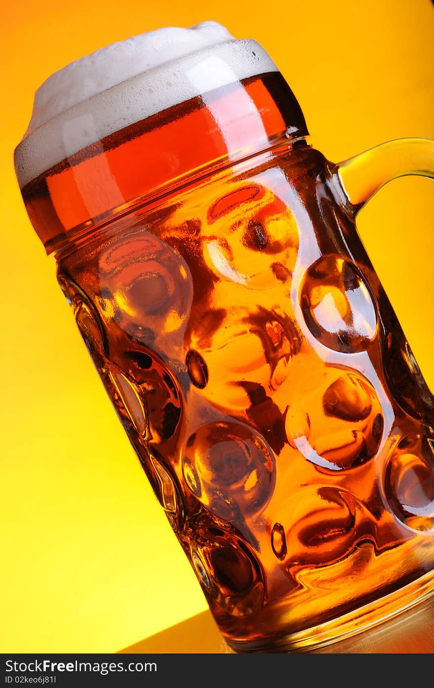 Mug of cold beer on orange background