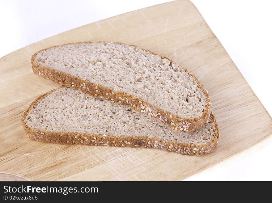 Two slices of brown bread lying on a wood board isolated on a white background