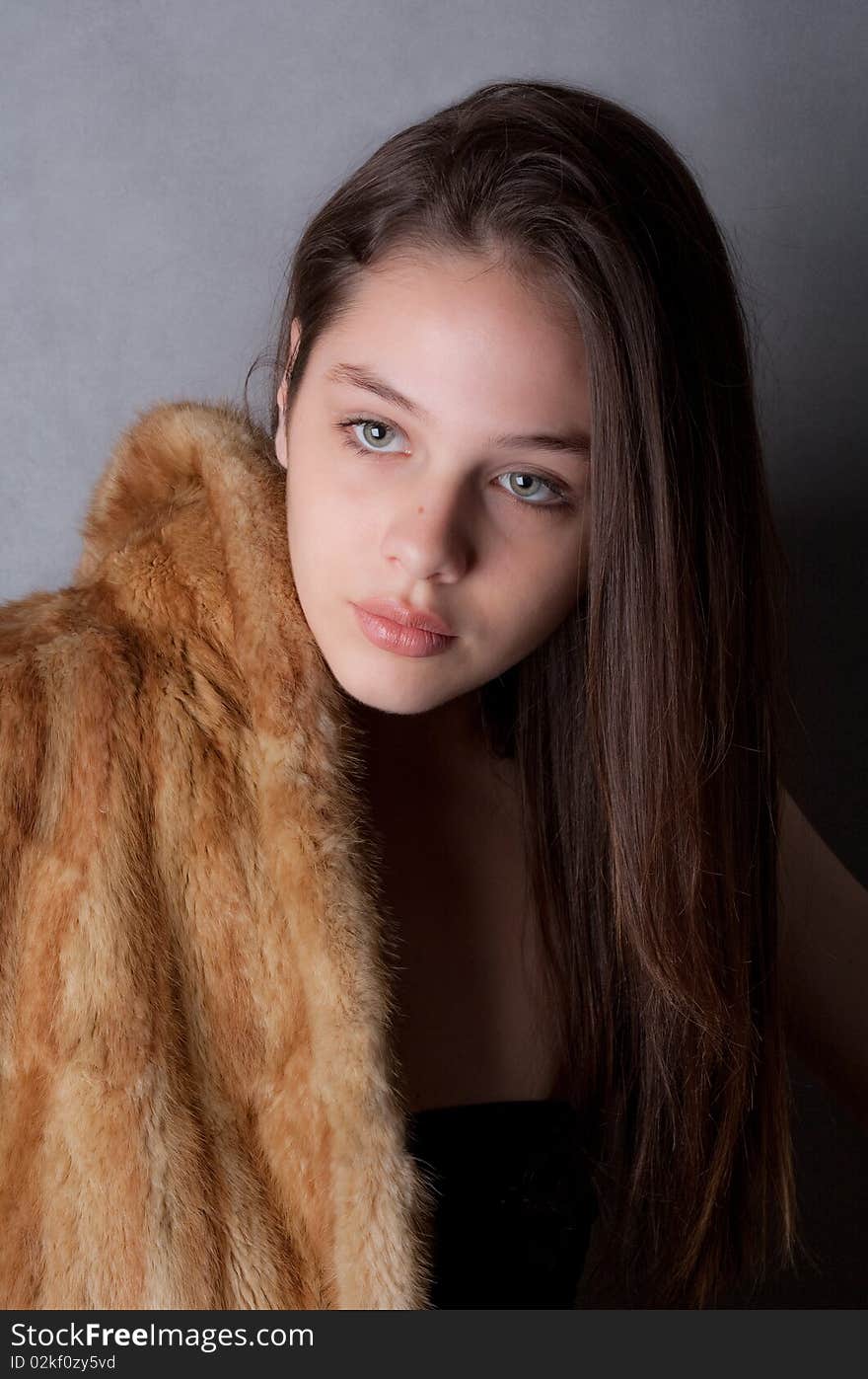 A portrait of a teenage model's face as she poses in a fur coat. A portrait of a teenage model's face as she poses in a fur coat