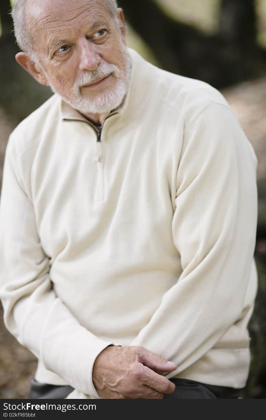 Portrait of  a Senior Man Sitting Outdoors Looking Away from Camera. Portrait of  a Senior Man Sitting Outdoors Looking Away from Camera