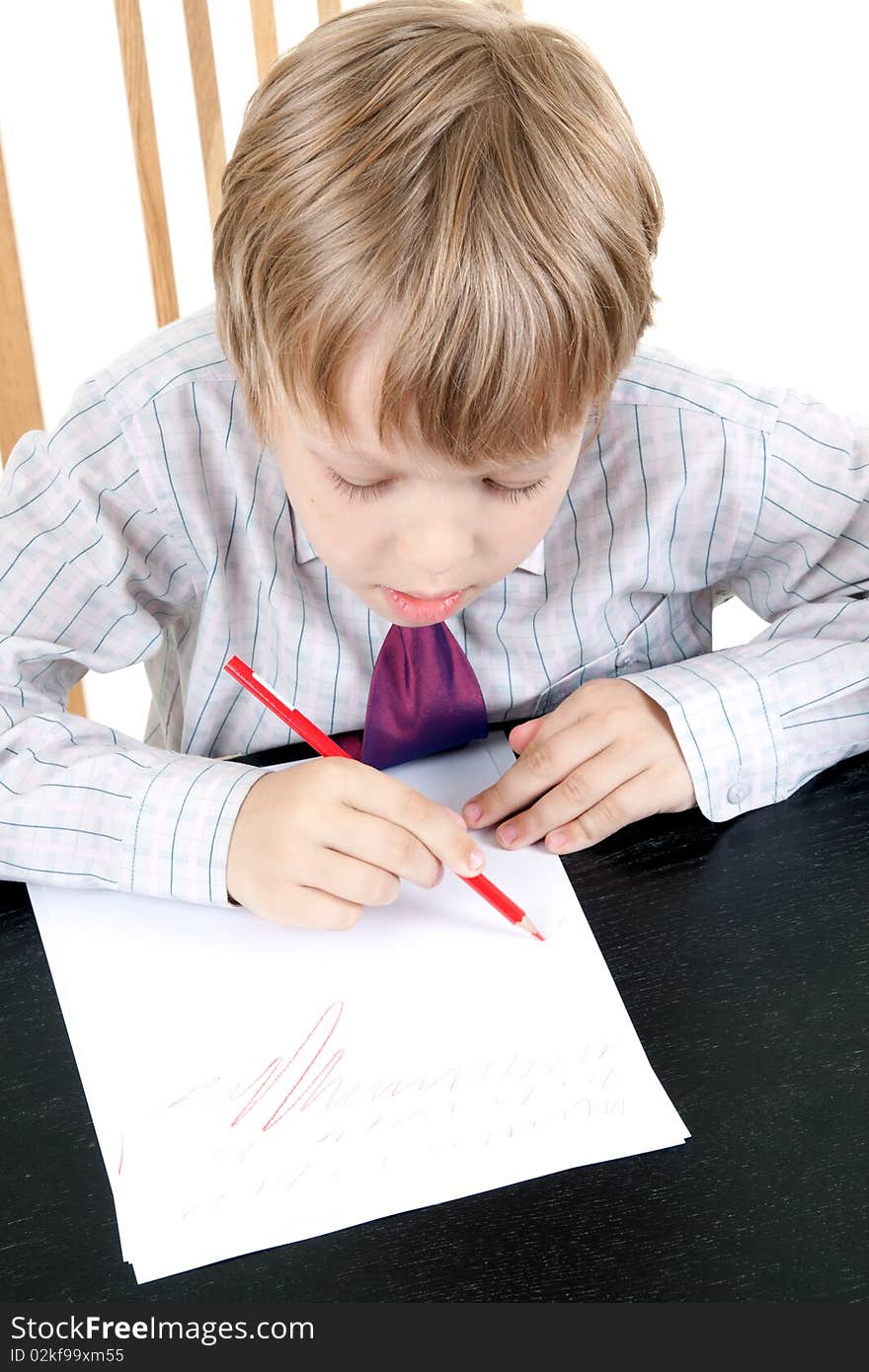 The boy draws with red pencil