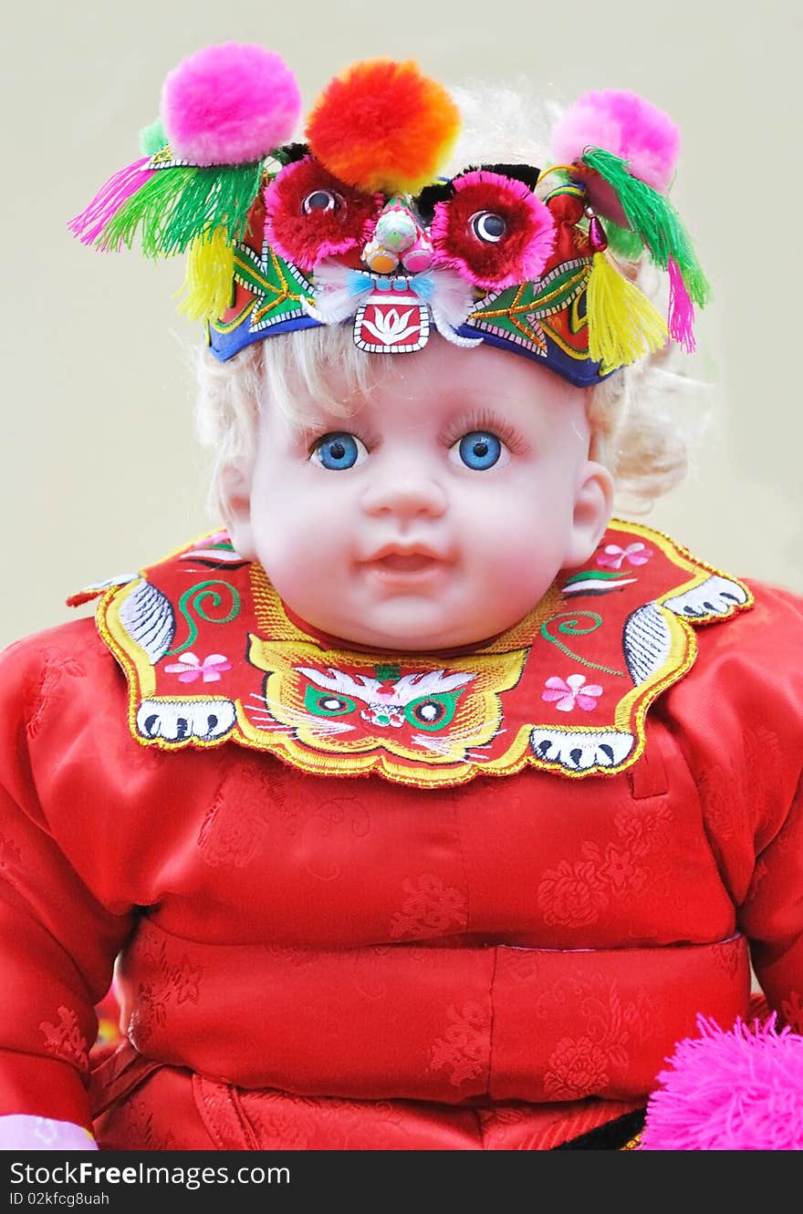 A doll girl in Chinese colorful traditional dress and accouterment, means happy and lucky for festival. A doll girl in Chinese colorful traditional dress and accouterment, means happy and lucky for festival.