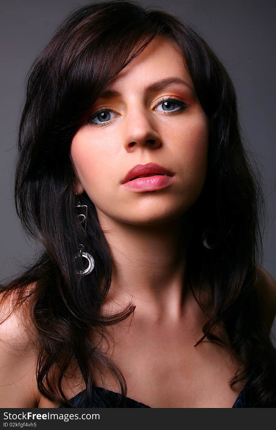 Young woman posing on grey background in black dress. Young woman posing on grey background in black dress