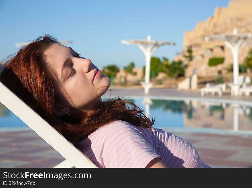 Young  woman relaxing in deck chair at resort hotel. Young  woman relaxing in deck chair at resort hotel