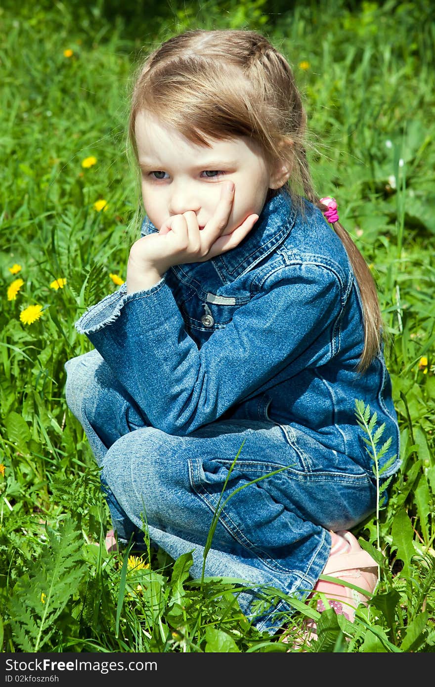 The thoughtful girl sits on a grass and looks in a distance. The thoughtful girl sits on a grass and looks in a distance