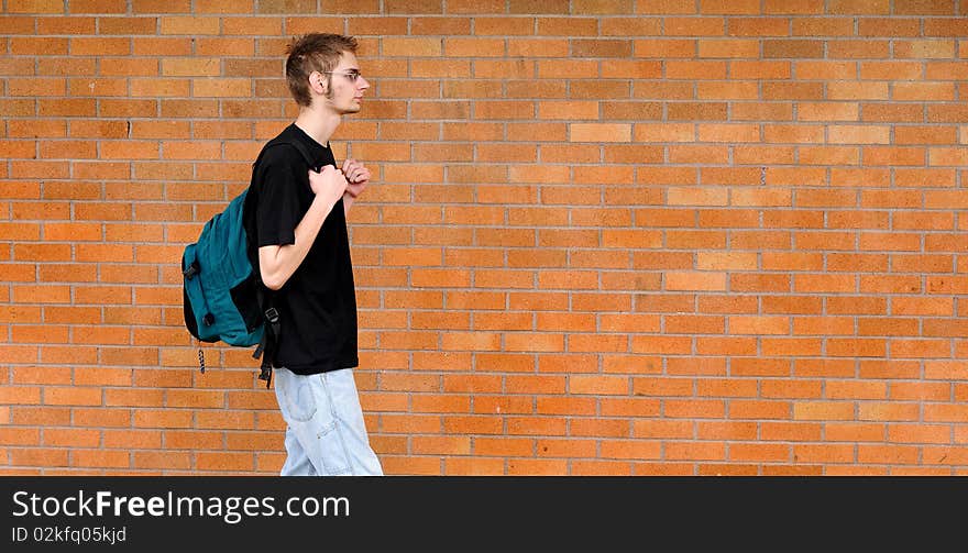 Student walking besides brick wall