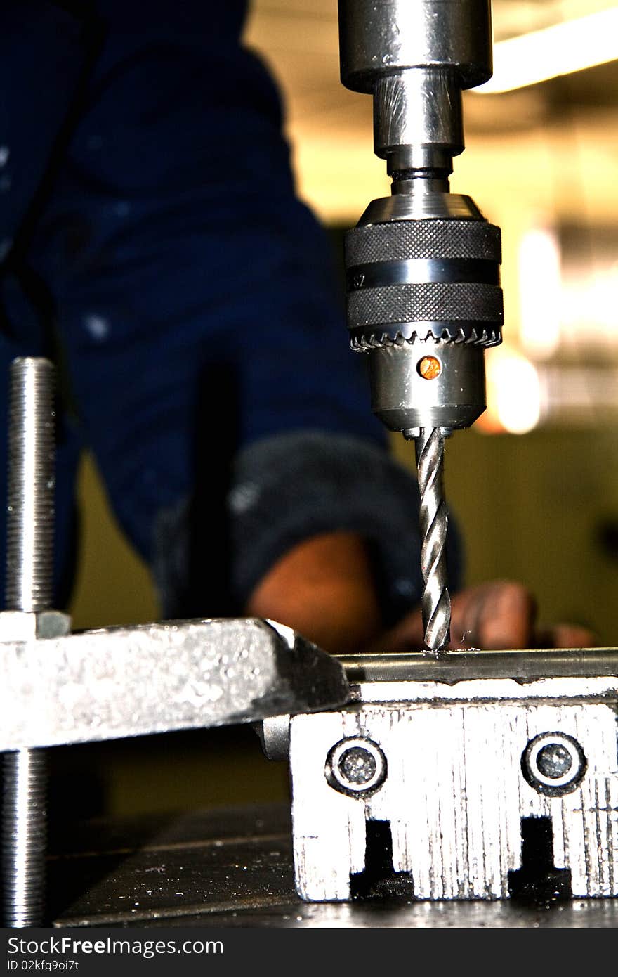 Close-up of an industrial drill press boring into a piece of metal. Close-up of an industrial drill press boring into a piece of metal