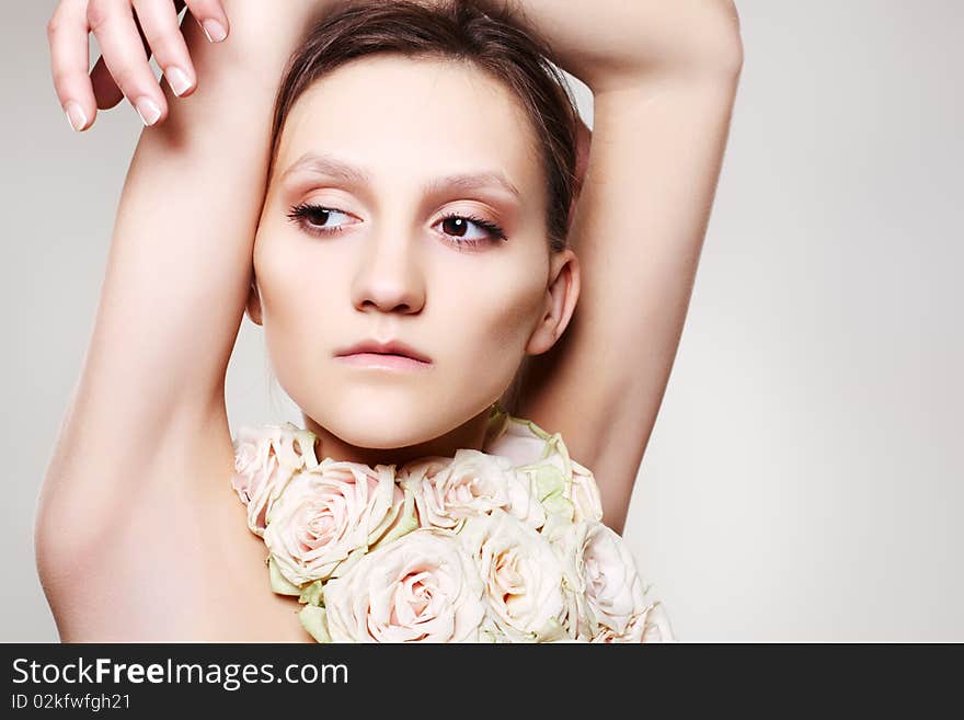 Beautiful woman in a rose necklace and with wedding make-up on gray background.