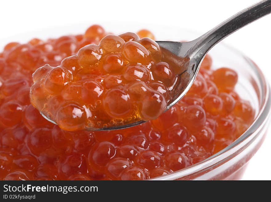 Red caviar in the little glass bow and spoon fragment isolated over white background