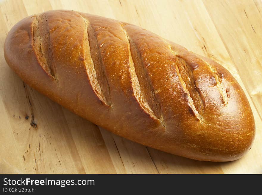 Shiny whole long bread over wooden desk background