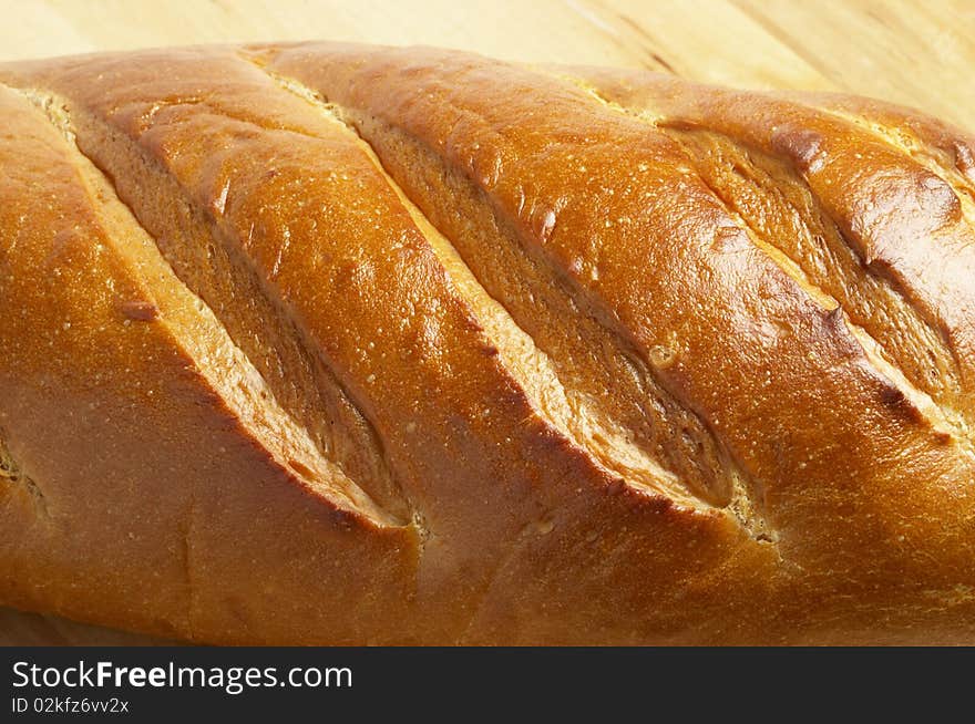 Shiny long bread fragment over wooden desk background