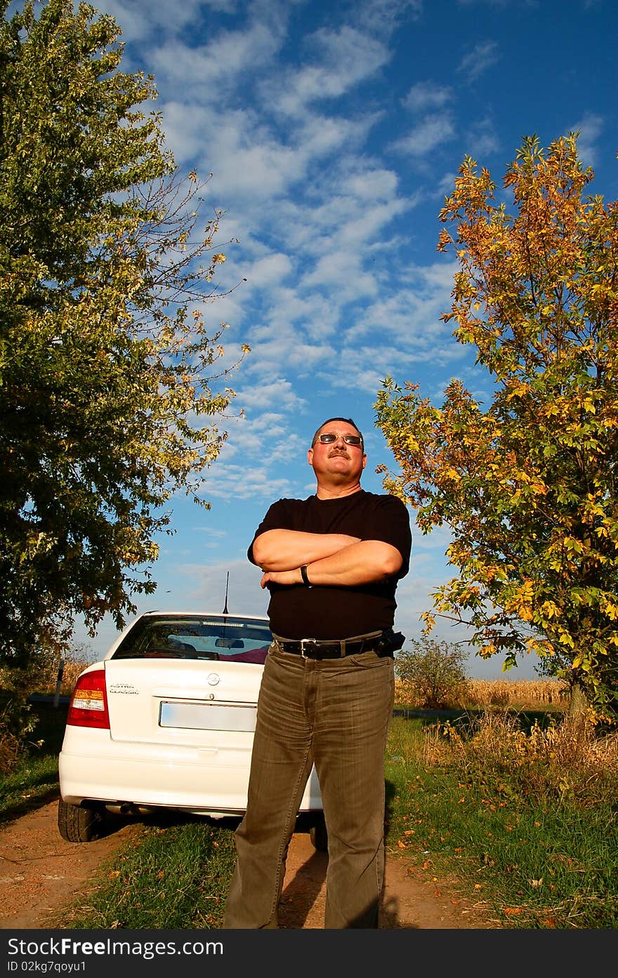 Proud man standing near his new car in a meadow. Proud man standing near his new car in a meadow.