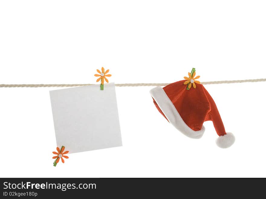 White blank and a red Santa's hat hanging on a rope. Isolated on white background. White blank and a red Santa's hat hanging on a rope. Isolated on white background