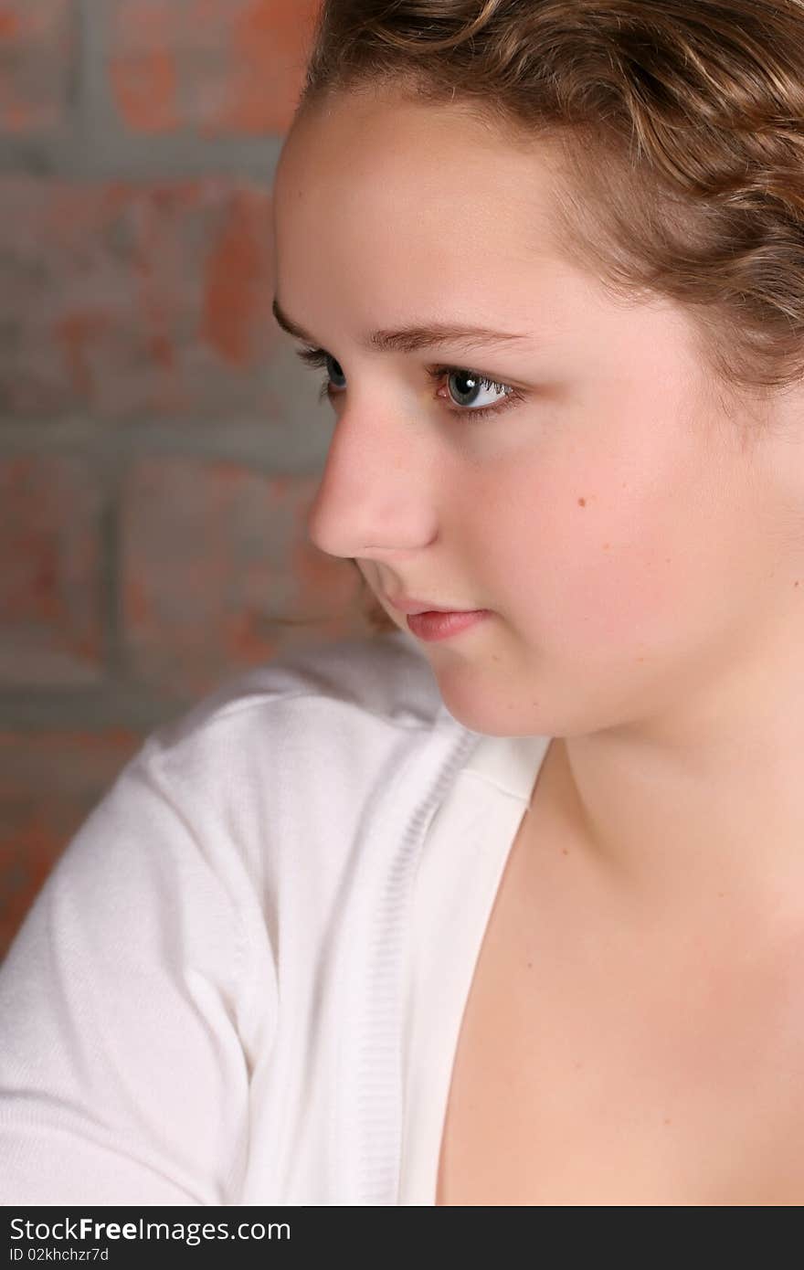 Beautiful teen with curly hair against a brickwall background