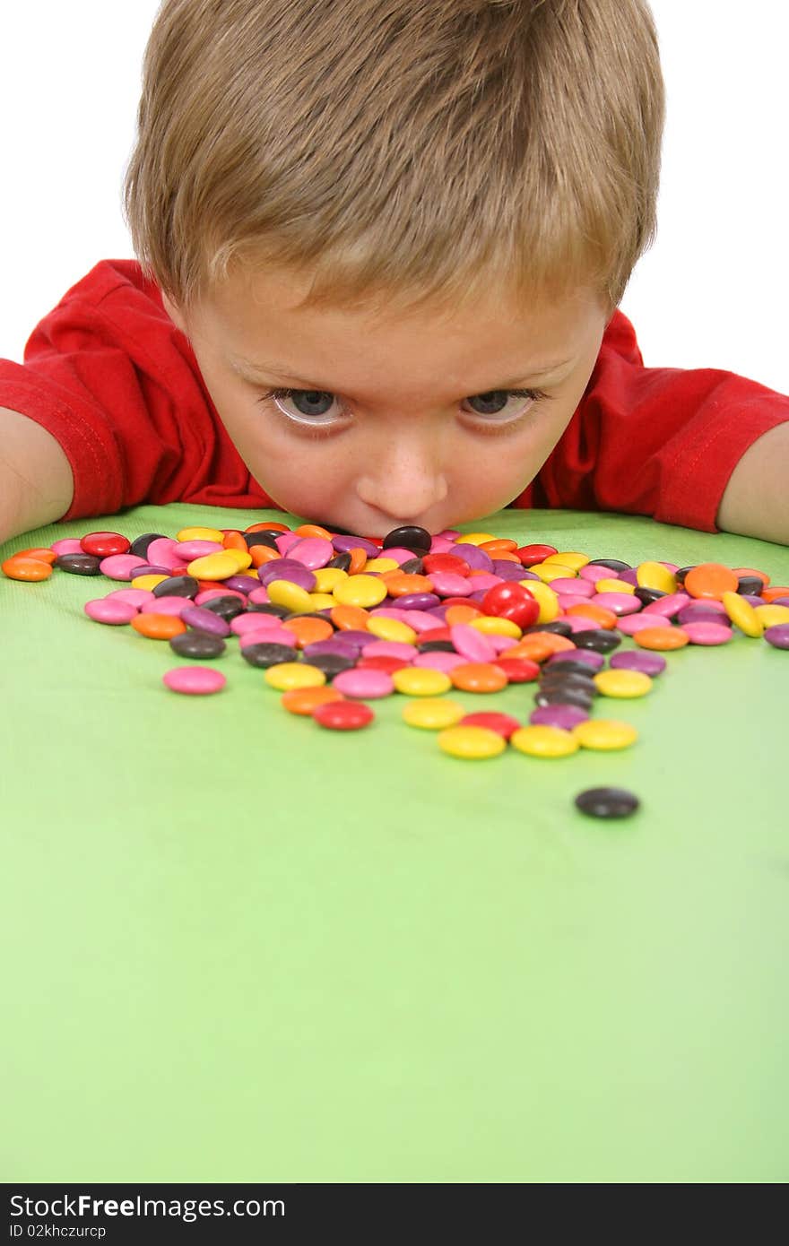 Young boy being with a table full of colorful sweets