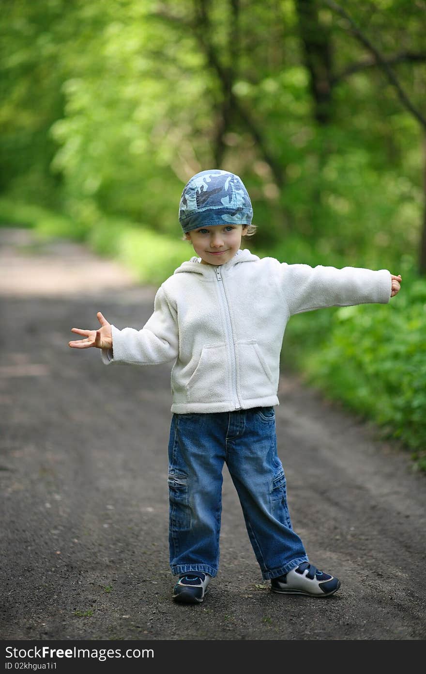 Little boy dressed in blue jeans and white blouse, standing in a forest. Little boy dressed in blue jeans and white blouse, standing in a forest.