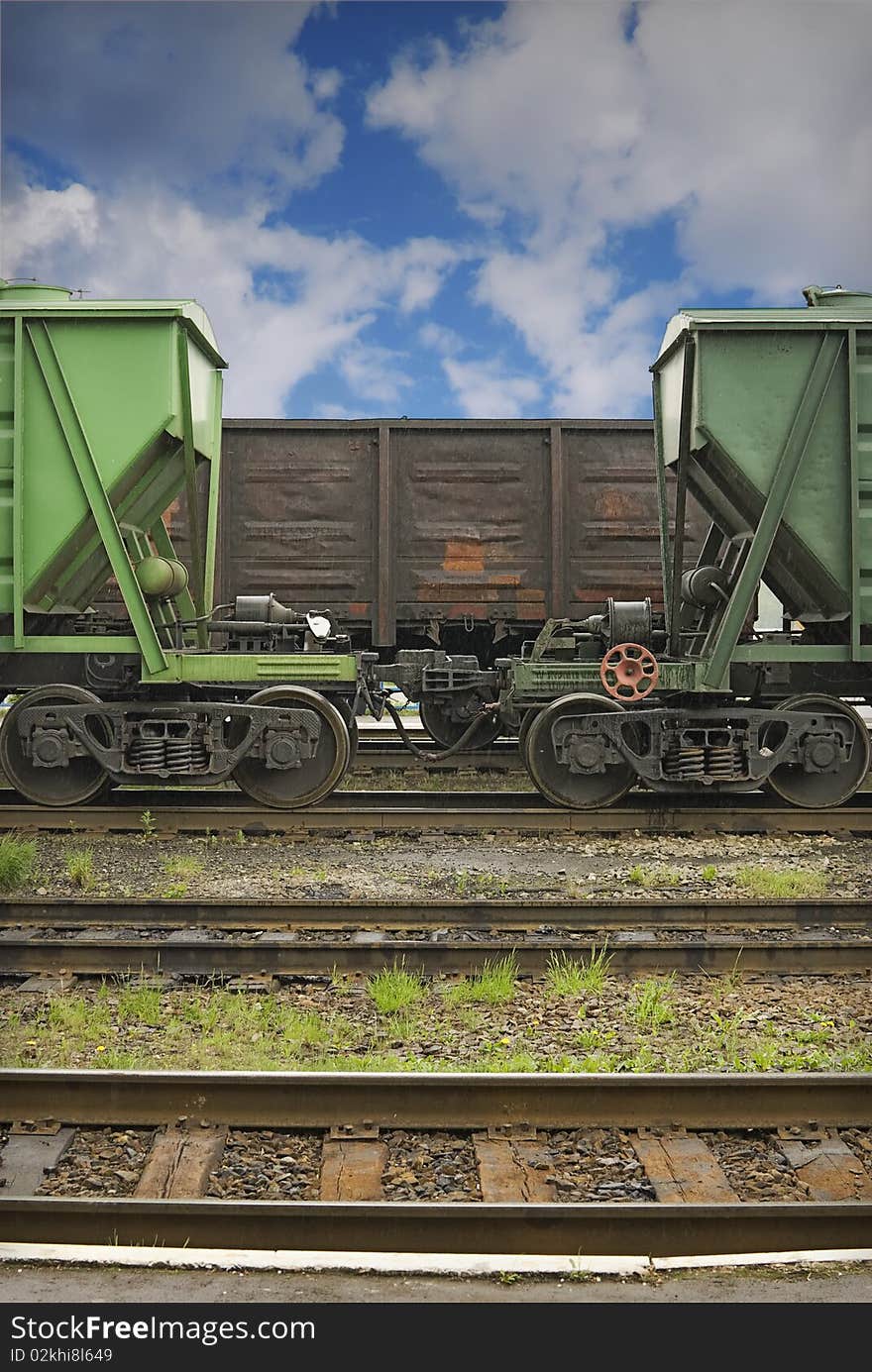 Cargo railway station. Three old railway cars for loose and common cargo are staying on the middle railways. There is a small summer rain.