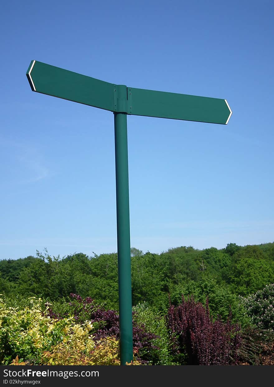 Sign post on a blue sky background with shrubs.