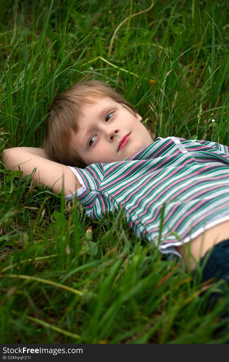 The little boy has laid down on a grass to dream. The little boy has laid down on a grass to dream