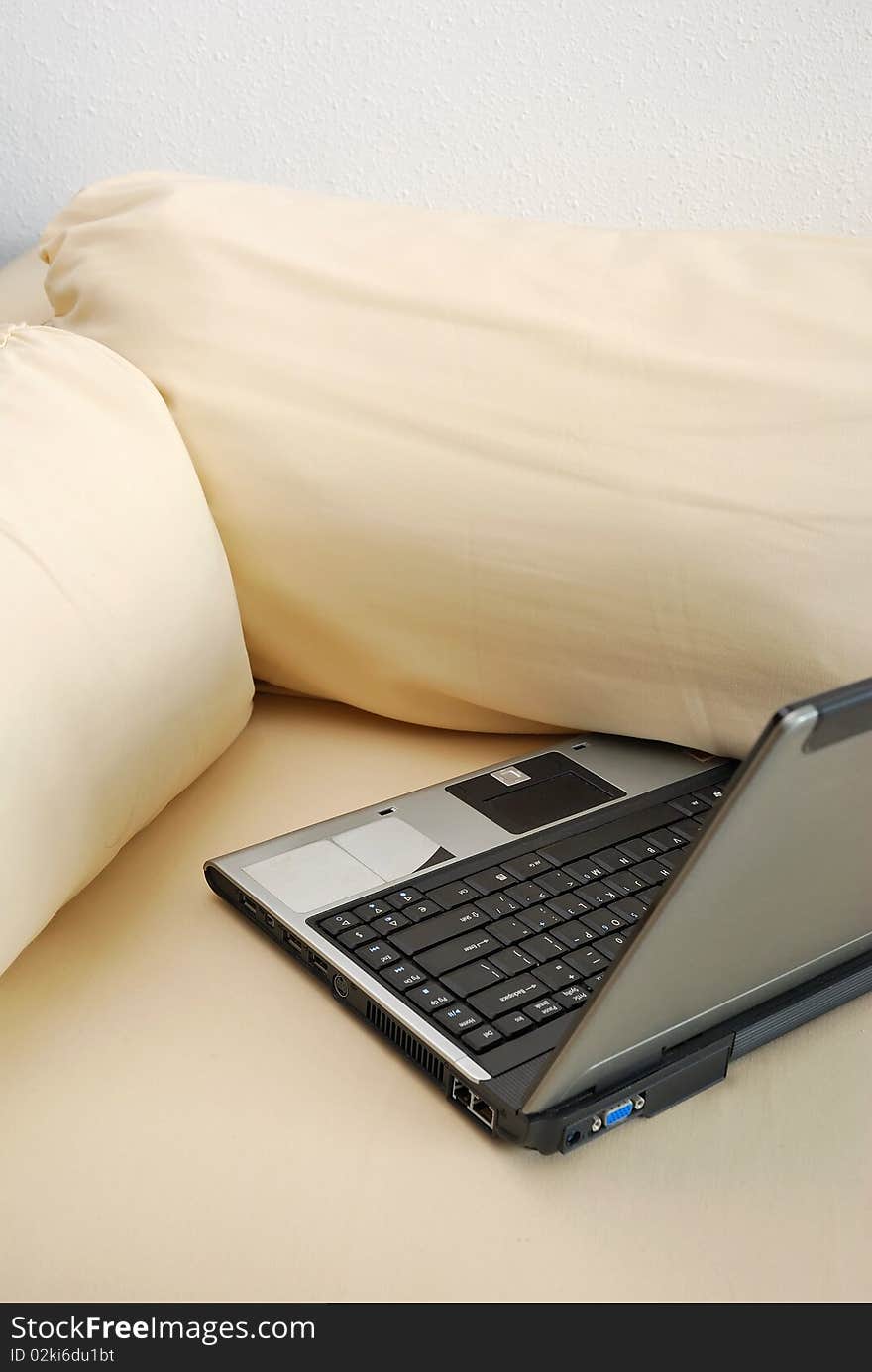 Laptop on sofa in room signifying concepts such as computers and technology, modern living and lifestyle, and business life.