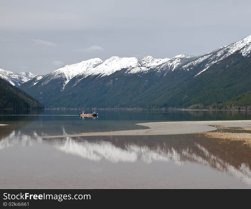 Two men troll in a small fishing boat on a lake for fish. Two men troll in a small fishing boat on a lake for fish