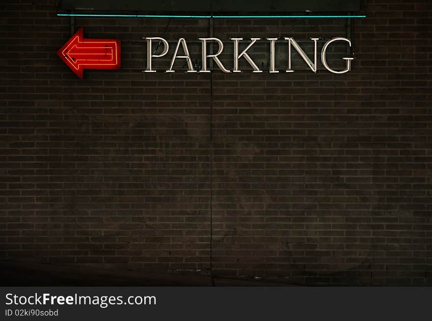 Parking sign and directional arrow, neon on a brick wall. Room for text and design. Parking sign and directional arrow, neon on a brick wall. Room for text and design.