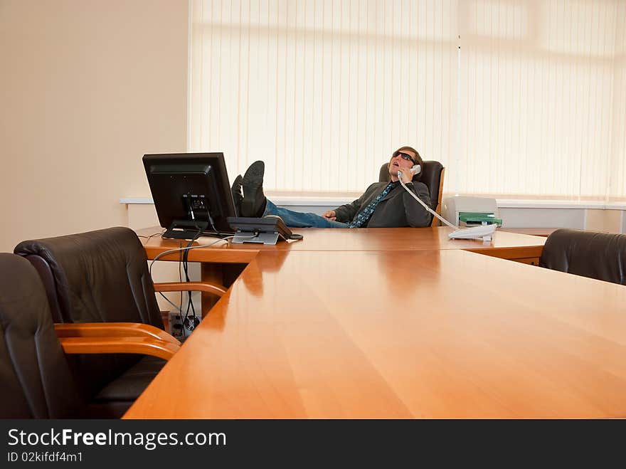 Businessman talking on the phone with his feet on the desktop