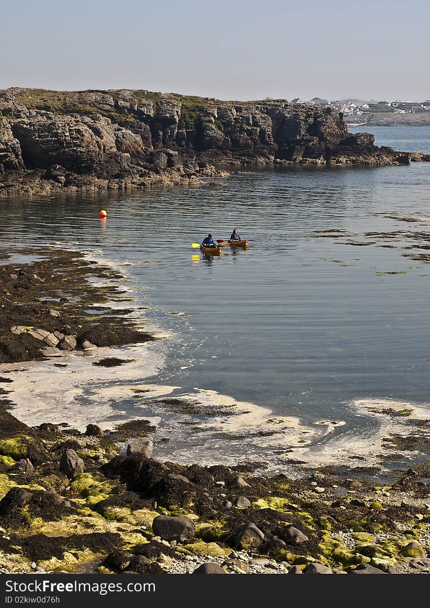 Canoes paddling on sea with coastal views in wales