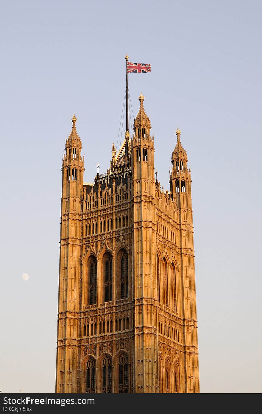 United Kingdom flag on Houses of Parliament from London, blue sky in background. United Kingdom flag on Houses of Parliament from London, blue sky in background