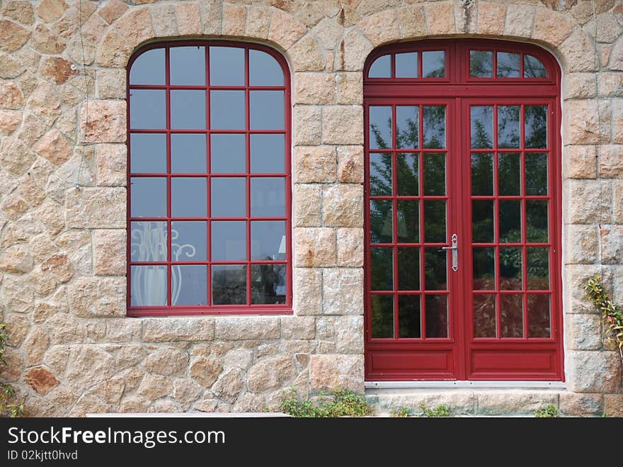 Red glassed door and windows with shutter in britany france